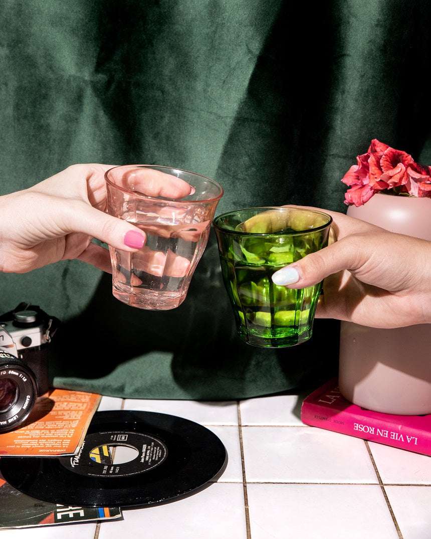 Duralex USA Le Picardie® Mix & Match Color Glass Tumbler Set 8.38oz - Set of 4, demonstrating a toast between two hands holding the pink and green tumblers.