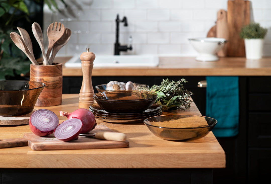 Duralex USA Lys Glass Dinnerware 18 Piece Set displayed on a kitchen countertop with various kitchen tools and ingredients, showcasing the elegant design.