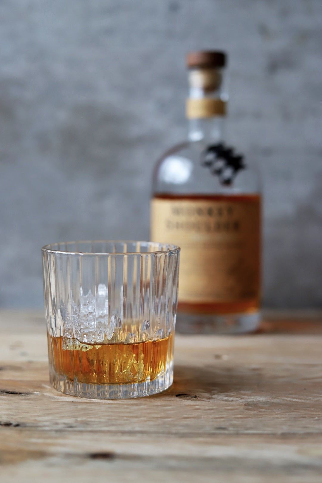 Manhattan Old Fashioned Glass - Set of 6 by Duralex filled with whiskey, set against a rustic wooden background.