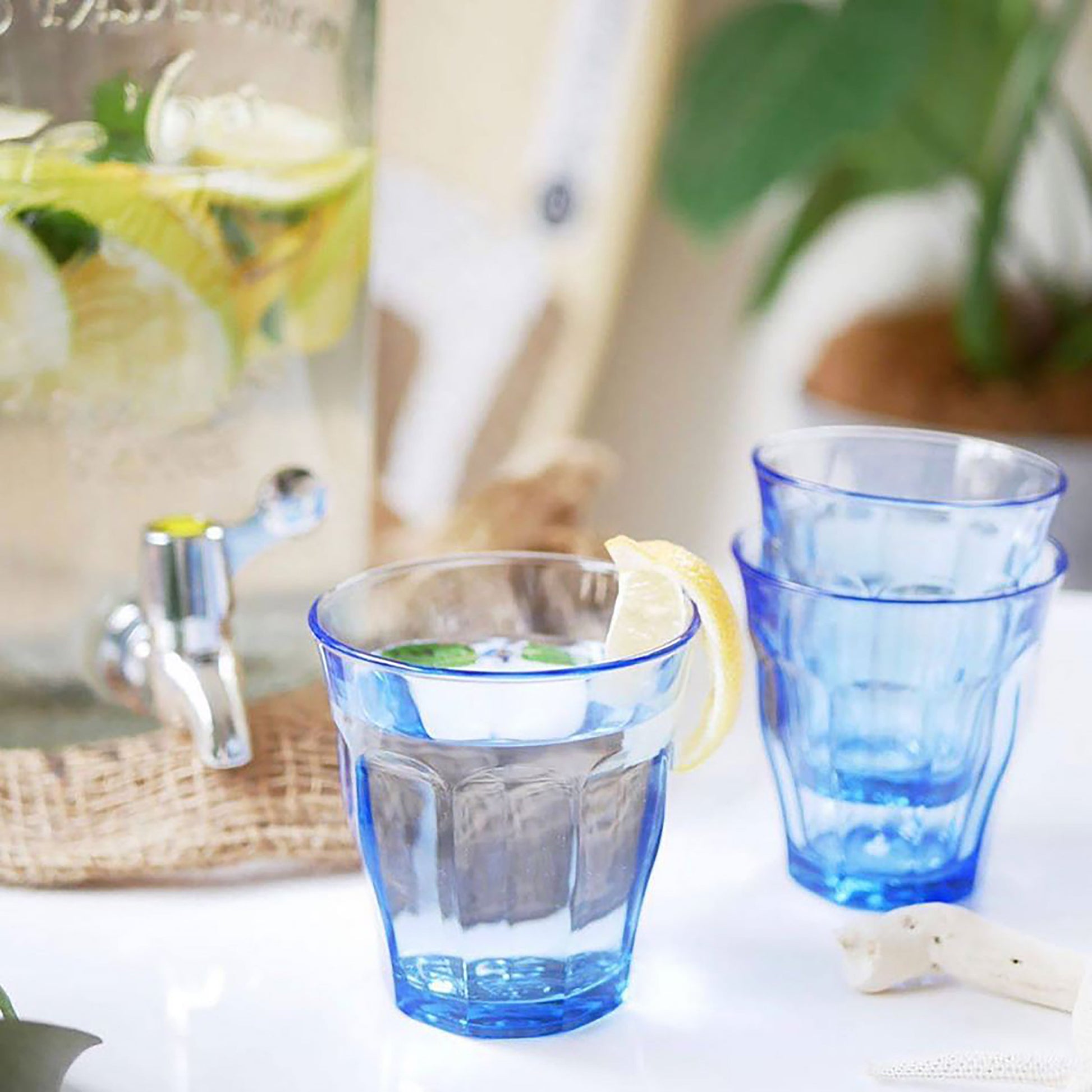 Duralex USA Le Picardie® Mix & Match Color Pink Blush & Marine Glass Tumbler Set 8.38oz displayed with lemon and mint, featuring two blue tumblers and a beverage dispenser.