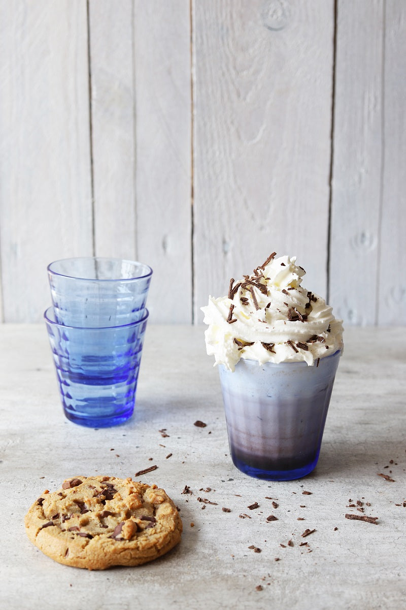 Prisme Marine Glass Tumblers by Duralex with desserts, showcasing the tumblers with a whipped cream treat and a cookie on a rustic table.