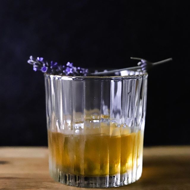 Manhattan Old Fashioned Glass - Set of 6 by Duralex filled with a cocktail and garnished with a lavender sprig.