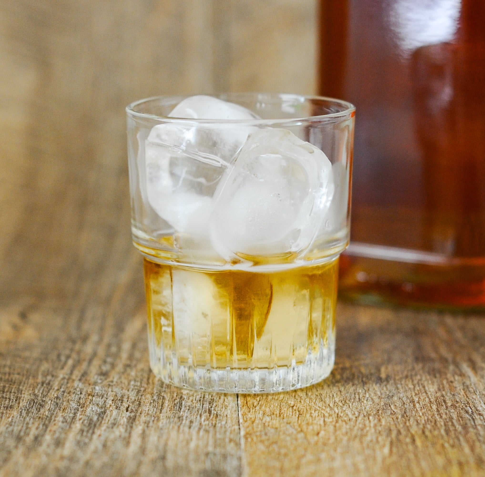 Glass tumbler by Duralex, part of the Empilable Stackable Glass Tumblers set of 6, filled with ice and whiskey, showcasing its fluted base.