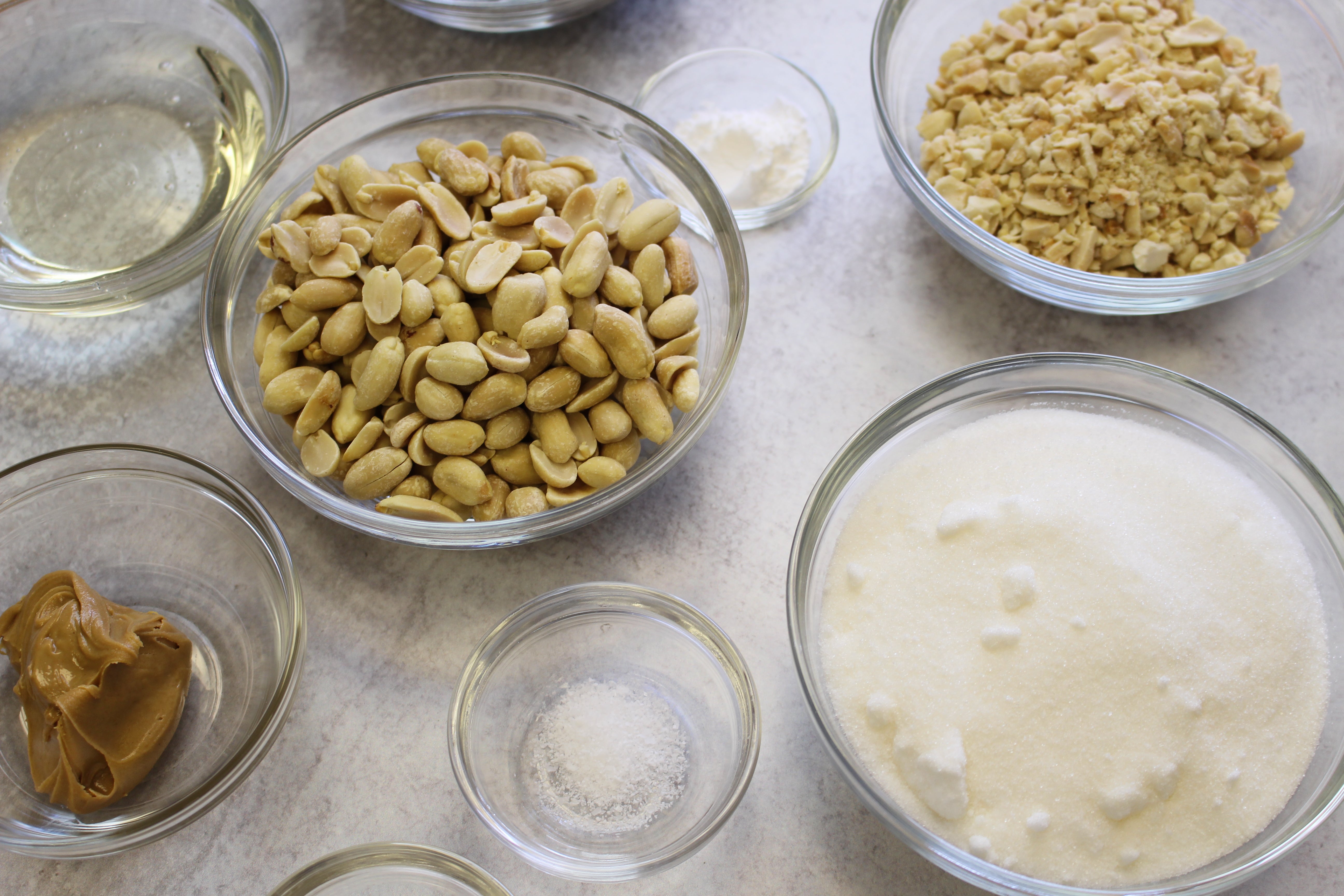 Organized ingredients for a recipe in Le Gigogne® Stackable Clear Glass Bowls by Duralex, including peanuts, sugar, and condiments.