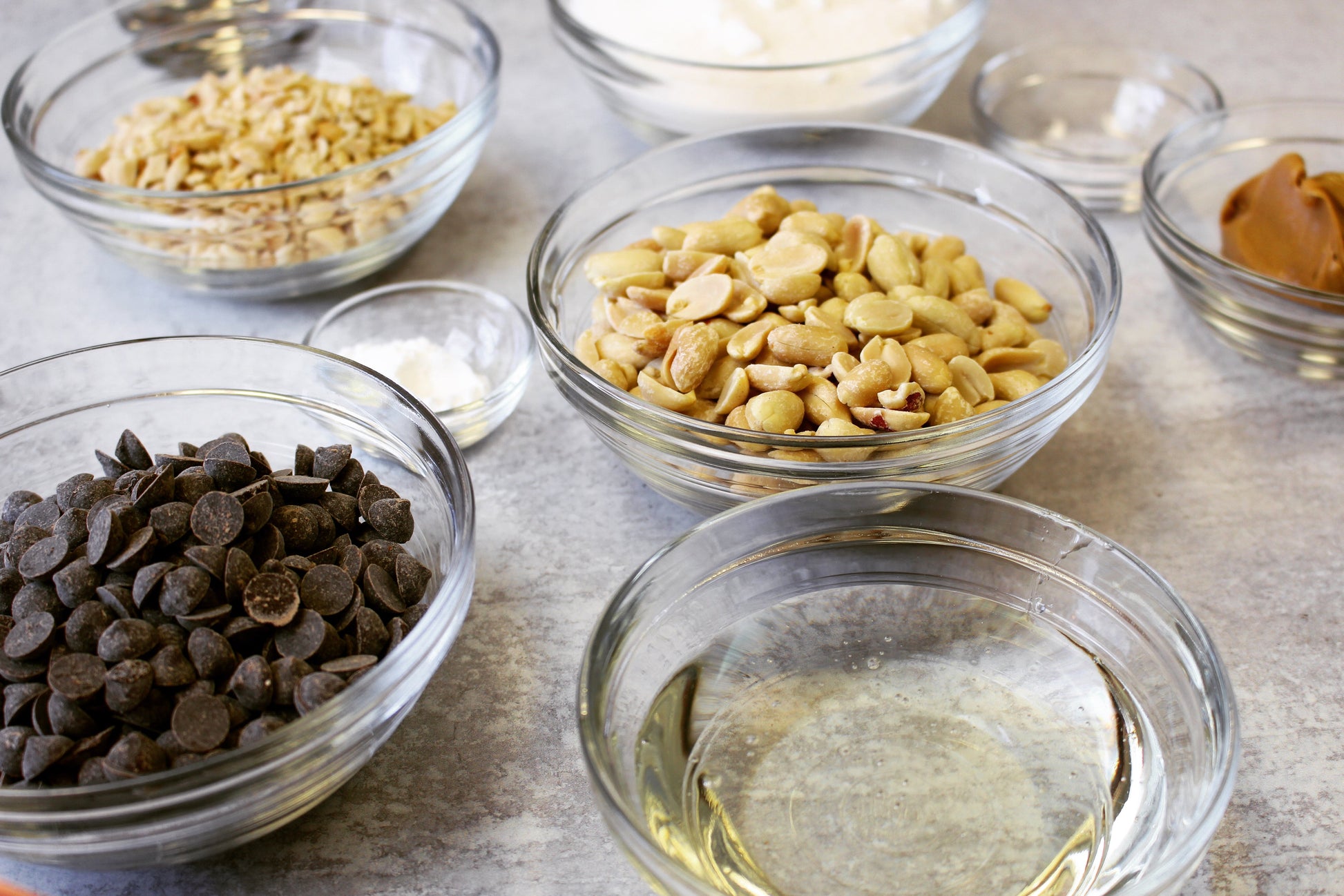Mixing ingredients in Le Gigogne® Stackable Clear Glass Bowls by Duralex, showcasing various food items like chocolate chips, peanuts, and spices.