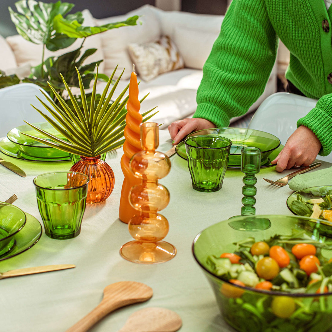 Lys Green Glass Table Bowl 9" from Duralex USA, complemented by a colorful table setting with green and orange bowls, showcasing a vibrant dining atmosphere.