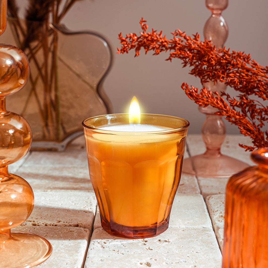 Le Picardie® Scented Candle by Duralex USA in a warm amber glass, with a glowing flame, surrounded by autumn-inspired decor, capturing the essence of Autumn Woods fragrance.