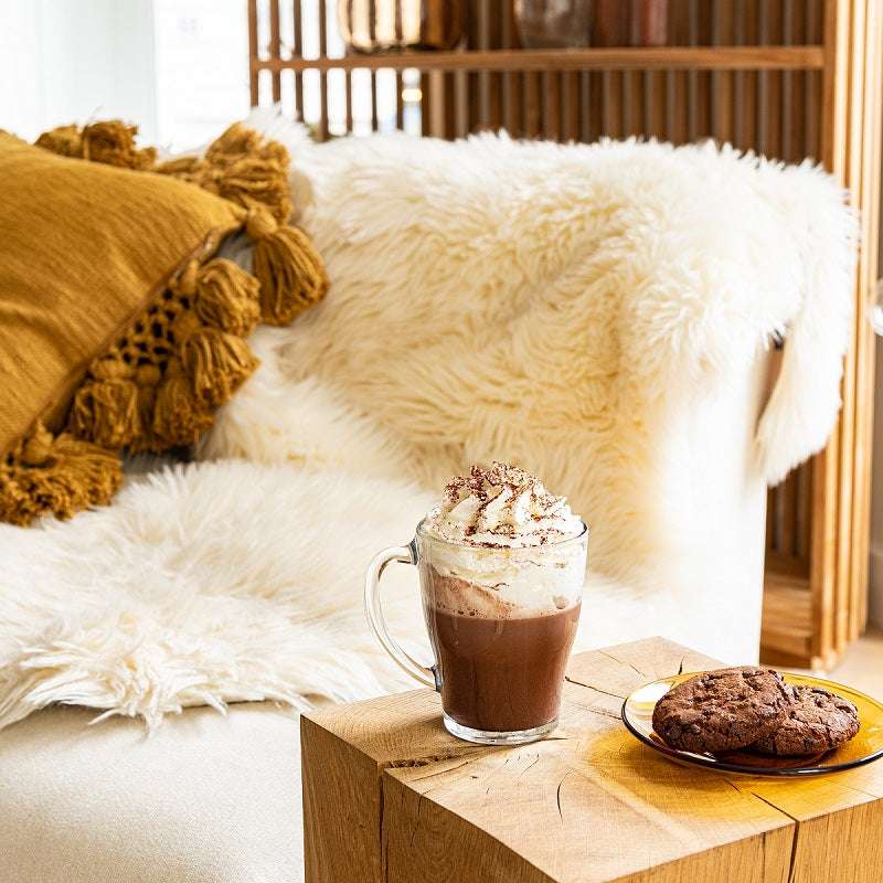 Duralex Cosy Glass Mug - Set of 6, featuring a glass mug filled with hot chocolate topped with whipped cream, placed on a cozy couch setting with cookies.