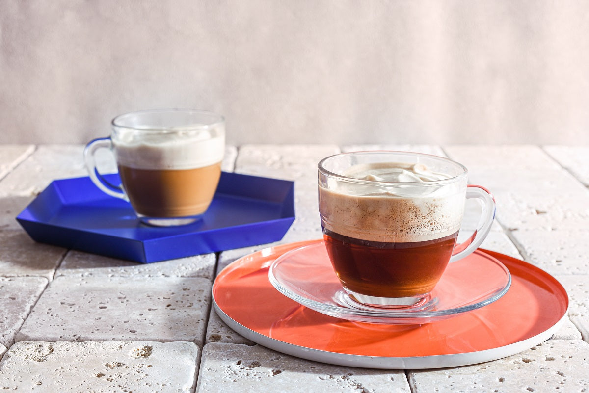 Le Gigogne® Glass Mug set by Duralex displayed with coffee drinks on colorful trays, perfect for serving beverages.
